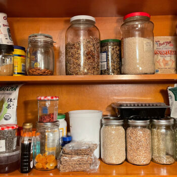 Glass jars filled with flour, grains, and beans on a shelf.